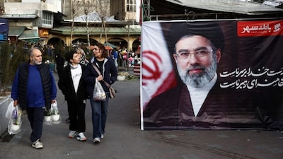 People walk next to a banner with a picture of Iran's new Supreme Leader, Mojtaba Khamenei, at Tajrish Bazaar, ahead of Nowruz, the Iranian New Year, amid the US-Israeli conflict with Iran, in Tehran, Iran, March 19, 2026. File Image/WANA via Reuters