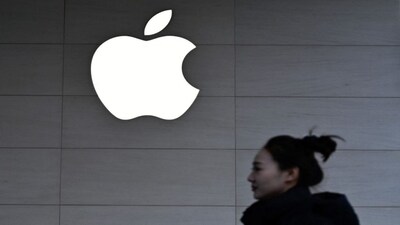 A woman walks past a logo of the Apple store in Beijing. File image/AFP