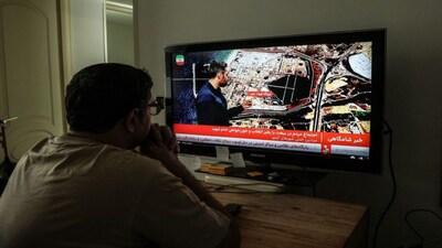 An Iranian man watches the news on Iranian State TV (IRIB) in Tehran as the war continues. File image/AFP