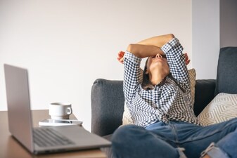 Tired from work, a young woman with a laptop lies on the couch.