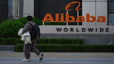 A man walks past a company logo during a tour at the Alibaba office in Beijing. File/AFP