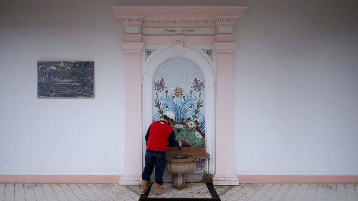 A man fills bottles at the Cachat spring, in Evian-les-Bains, eastern France, on December 16, 2025.