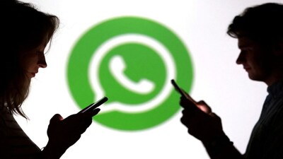 Teenagers pose for a photo while holding smartphones in front of a Whatsapp logo. File image/Reuters