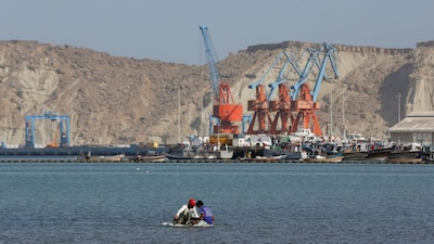 Boys sit on a piece of styrofoam sheet as they search for crabs in front of the Gwadar port, Pakistan, April 11, 2017. File Image/Reuters
