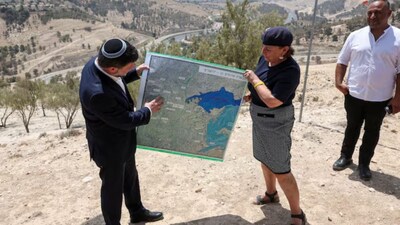 Israeli Finance Minister Bezalel Smotrich and a woman hold a map that shows the long-frozen E1 settlement scheme, that would split East Jerusalem from the occupied West Bank, on the day of a press conference near the Israeli settlement of Maale Adumim, in the Israeli-occupied West Bank, August 14, 2025. REUTERS