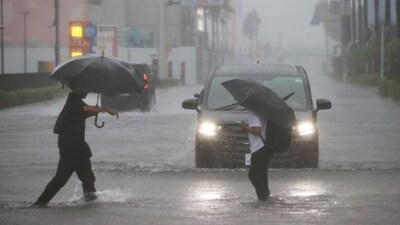 People wade through a flooded road as heavy rain falls amid weather patterns due to Typhoon Dujuan in Funabashi, Chiba Prefecture on September 21, 2026. (AFP)