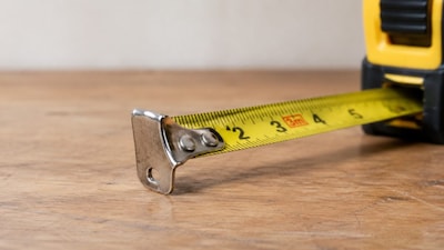 A close-up of a tape measure showing the movable metal hook at its end. Photo: AI generated