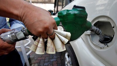 A worker fills diesel in a car as he holds 500 Indian rupee banknotes at a fuel station in Kolkata, India. File/Reuters