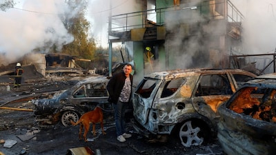 A resident with a dog looks on at the site of private car garages hit by a Russian missile strike, amid Russia's attack on Ukraine, in Kyiv, Ukraine October 7, 2026. Photo: Reuters
