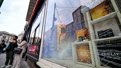 A shattered shop window is seen as pedestrians stand nearby following clashes between police and protesters during demonstrations over rising living costs and poor public services, in Milan, Italy, on Monday. Reuters