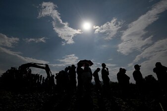 People stand next to an excavator near the site where an illegal gold mine collapsed. (File/AFP)