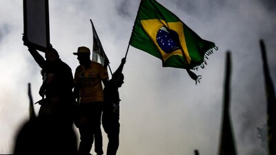 A supporter of Brazil’s right-wing senator and presidential candidate Flavio Bolsonaro of the Liberal Party (PL) waves a natinal flag during a campaign rally on the eve of the general election in the Bangu neighborhood, in Rio de Janeiro’s West Zone, on October 3, 2026. AFP