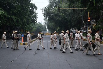 Delhi Police personnel cross a street ahead of a protest