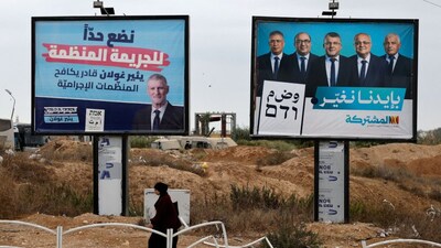 A Bedouin woman walks past pre-election campaign billboards featuring Yair Golan of the Democrats party and leaders of the Joint List in the Bedouin city of Rahat, southern Israel, on October 12, 2026. (Photo: Amir Cohen/Reuters) 