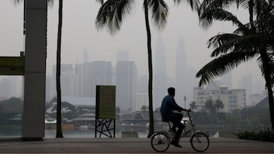 A man cycles with Kuala Lumpur’s skyline in the background shrouded in haze from regional wildfires, in Kuala Lumpur, Malaysia, October 15, 2026. File Image/Reuters