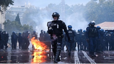 A police officer with paint walks near a fire during a demonstration against the "high cost of living", in Montpellier, southern France, on October 17, 2026 as part of a nationwide call for mobilisation bringing together various groups expressing their anger: former "Yellow Vest", secondary school and university students, climate activists and even farmers. Image- AFP