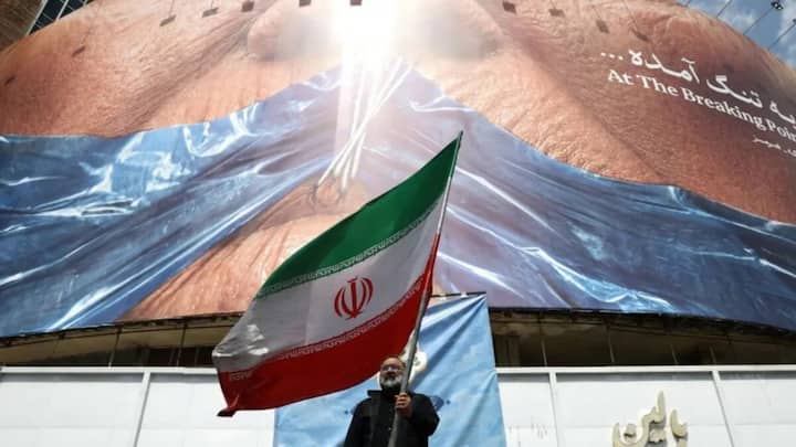 A man holds an Iranian flag near an anti-US billboard depicting US President Donald Trump and the Strait of Hormuz, in Tehran, May 2, 2026. File- Reuters 
