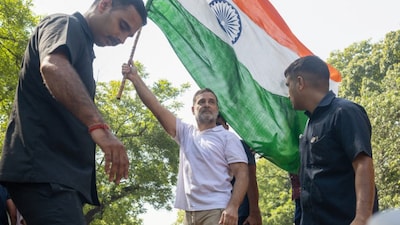 Rahul Gandhi holds an Indian flag as he stands atop a barricade during a protest organised by opposition parties demanding the resignation of Chief Election Commissioner Gyanesh Kumar in New Delhi. Reuters