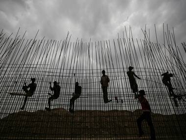 Labourers are silhouetted as they fasten iron rods together at the construction site of a commercial complex, in the western Indian city of Ahmedabad