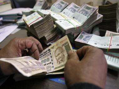 An employee counts Indian rupee notes at a cash counter inside a bank in Agartala