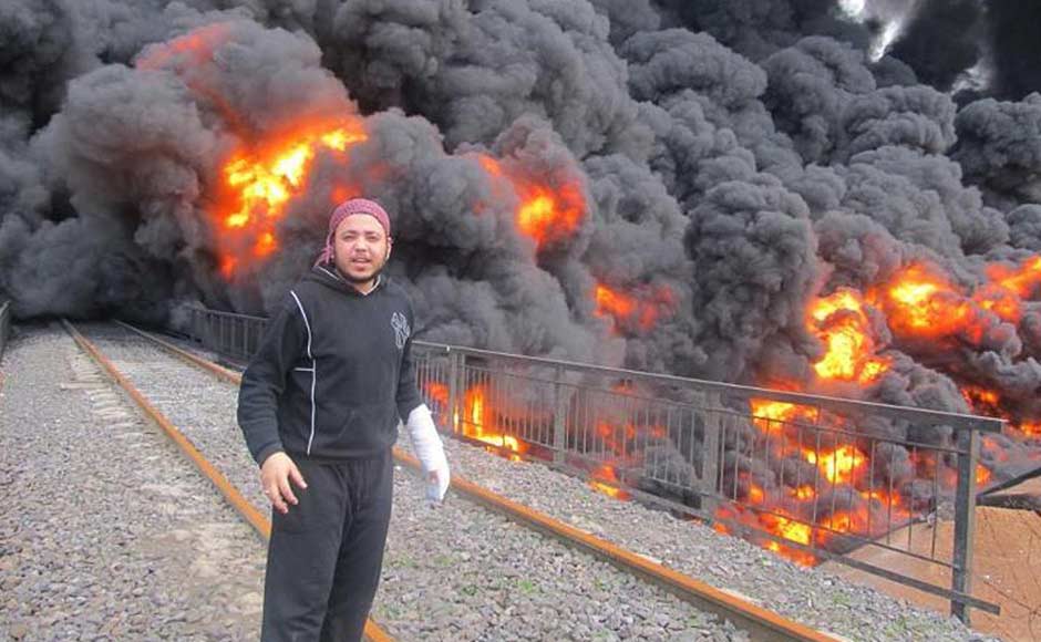 In this citizen journalism image provided by the Local Coordination Committees in Syria anti-Syrian regime activist Khaled Abu-Salah stands in front of flames and black smoke from a bombed oil pipeline, in Baba Amr neighbourhood in Homs province, central Syria. Activists accused regime forces of hitting the pipeline. AP Photo/Local Coordination Committees in Syria. In this citizen journalism image provided by the Local Coordination Committees in Syria anti-Syrian regime activist Khaled Abu-Salah stands in front of flames and black smoke from a bombed oil pipeline, in Baba Amr neighbourhood in Homs province, central Syria. Activists accused regime forces of hitting the pipeline. AP Photo/Local Coordination Committees in Syria.