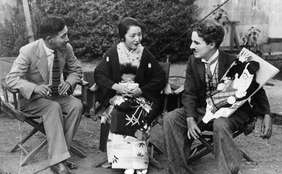 English actor Sir Charlie Chaplin, (right), receives a portrait of himself from a Japanese actress and her husband, painted by a Japanese artist. Getty Images English actor Sir Charlie Chaplin, (right), receives a portrait of himself from a Japanese actress and her husband, painted by a Japanese artist. Getty Images