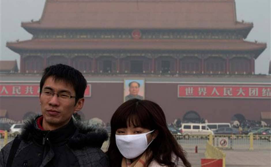 A woman wears a mask as she visits Tiananmen Square in Beijing: AP A woman wears a mask as she visits Tiananmen Square in Beijing: AP