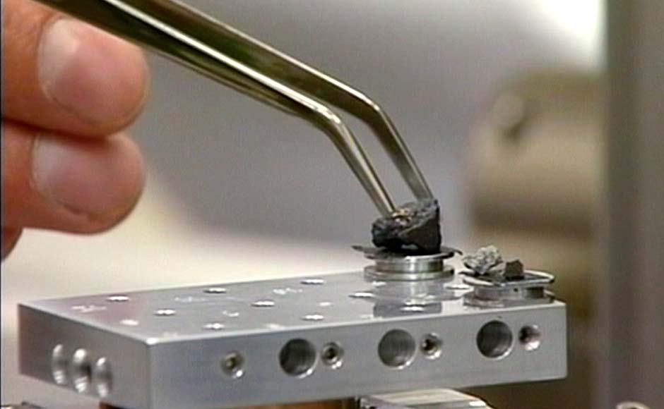 In this frame grab taken from AP video, a researcher touches a piece of a meteorite in a laboratory. The largest one is one centimeter in diameter, the smallest is about one millimeter. AP
