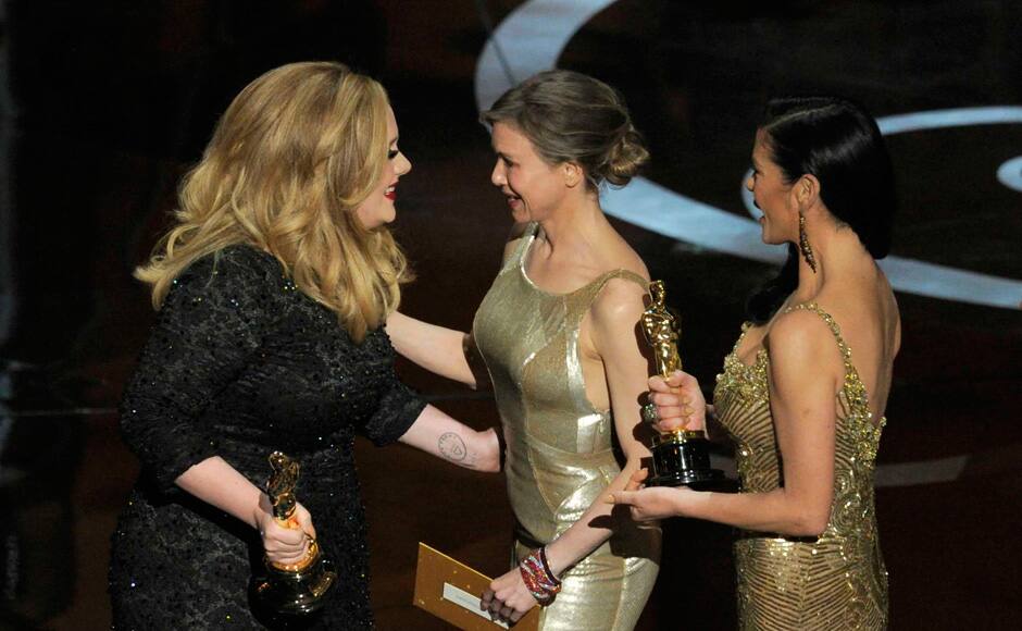 Actors Catherine Zeta-Jones, right, and Renee Zellweger, center, present the award for best original song to singer Adele for 