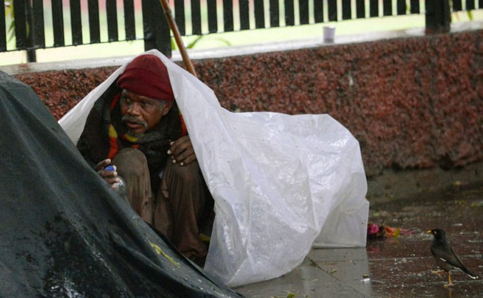 A homeless man takes shelter under a tarpaulin sheet. AFP A homeless man takes shelter under a tarpaulin sheet. AFP