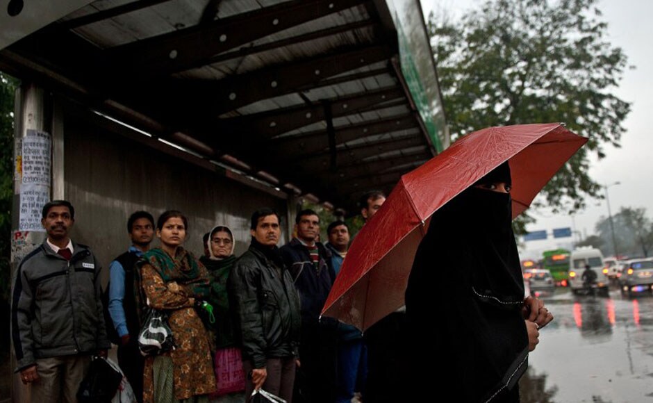 Commuters take shelter at a bus stop as heavy rains lash the city, bringing down the mercury and throwing normal life out of gear. AFP Commuters take shelter at a bus stop as heavy rains lash the city, bringing down the mercury and throwing normal life out of gear. AFP