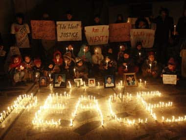Pakistani Shiite Muslim children hold candles and banners next to photographs of people, who were killed by a bomb blast in market on 23 Feb. AP