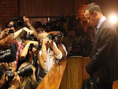 Photographers take photos of Olympic athlete Oscar Pistorius as he stands in the dock during his bail hearing at the magistrates court in Pretoria. AP