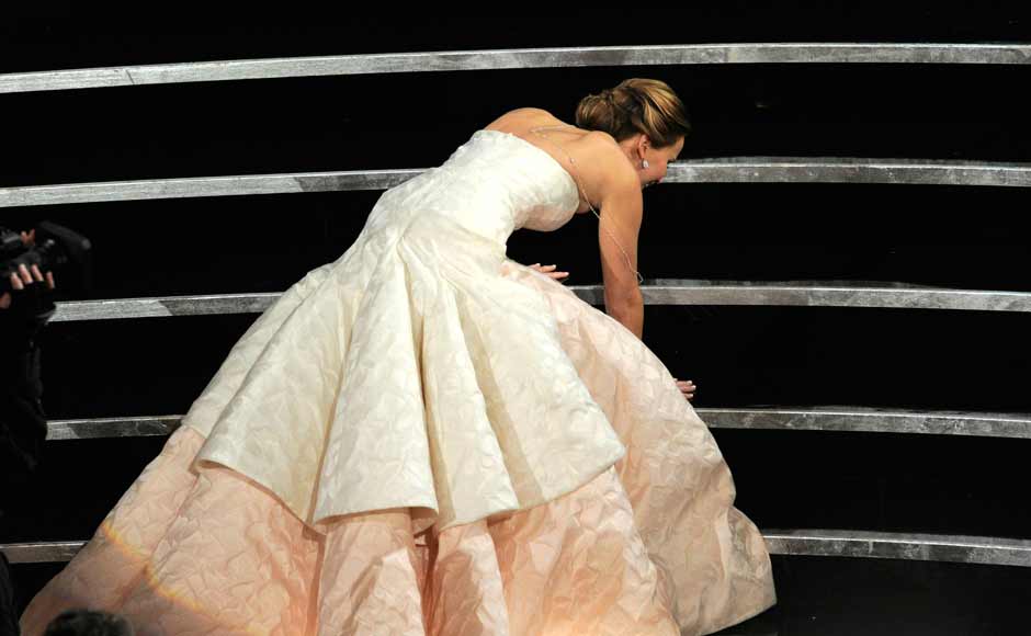 Jennifer Lawrence stumbles as she walks on stage to accept the award for best actress in a leading role for 