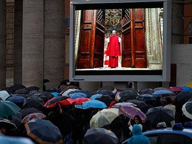 People watch on a video monitor in St. Peter's Square as Monsignor Guido Marini, master of liturgical ceremonies, closes the double doors to the Sistine Chapel in Vatican City. AP