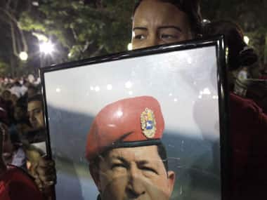 A Hugo CHavez supporter holds his photo. AP