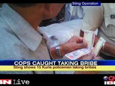 Cops caught on tape taking bribes. Image courtesy: ibnlive