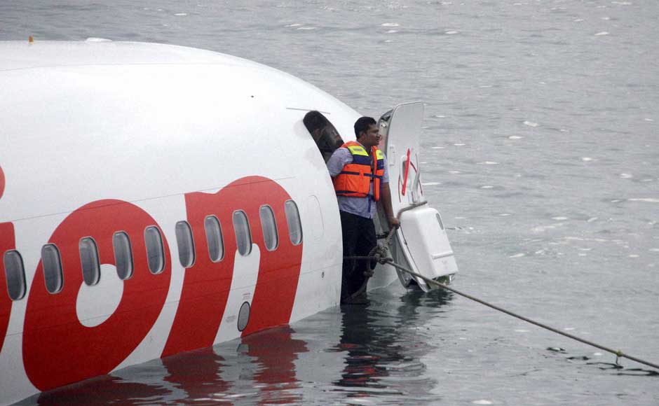 In this photo released by Indonesian Police, a rescue worker stands at the doorway of a crashed Lion Air plane on the water near the airport in Bali, Indonesia on 13 April 2013. AP/PTI In this photo released by Indonesian Police, a rescue worker stands at the doorway of a crashed Lion Air plane on the water near the airport in Bali, Indonesia on 13 April 2013. AP/PTI