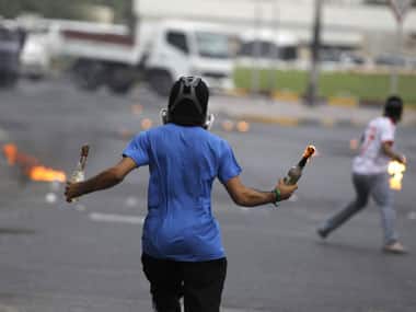 A protester with Molotov cocktails runs towards riot police during clashes after an anti-government protest in the village of Diraz, west of Manama. Reuters