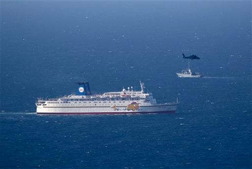 An Israeli military naval ship and an Israeli air force helicopter operate next to a cruise ship off the coast of Haifa. AP