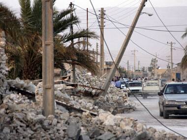 Vehicles make their way along structures destroyed by an earthquake which struck Iran. AP