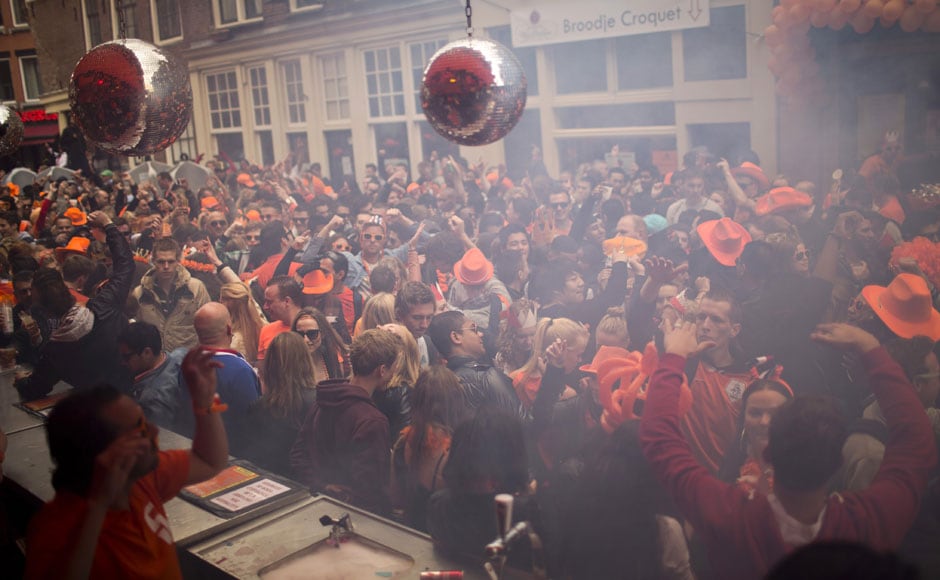 People dance on the streets of Amsterdam, wearing orange hats, in celebration of their new king. AP People dance on the streets of Amsterdam, wearing orange hats, in celebration of their new king. AP