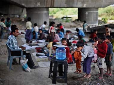A boy drinks water, as others wait at a free school run under a mass transit bridge: AP