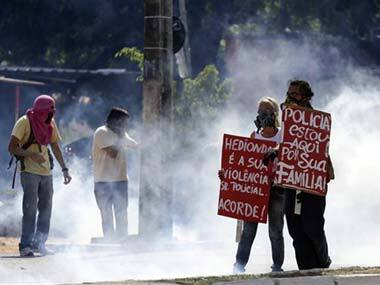 Protestors stand amidst tear gas. AP