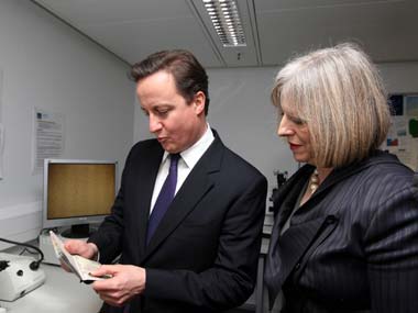 File photo of Britain's PM David Cameron and Home Secretary Theresa May looking at passports during a visit to UK Border Agency staff. Reuters