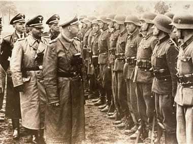 The June 3, 1944 photo provided by the US Holocaust Memorial Museum shows Heinrich Himmler, centre, SS Reichsfuehrer-SS, head of the Gestapo and the Waffen-SS, and Minister of the Interior of Nazi Germany as he reviews troops of the Galician SS-Volunteer Infantry Division Michael Karkoc a top commander whose Nazi SS-led unit is blamed for burning villages filled with women and children lied to American immigration officials to get into the United States and has been living in Minnesota. AP 