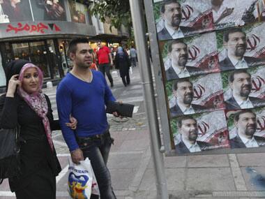 Iranians walk past posters of the presidential candidate Mohsen Rezaei, a former Revolutionary Guard commander. AP