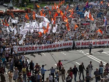 Russian opposition protesters some holding portraits of political prisoners shout anti-Putin slogans as they march through a street next to the Kremlin in Moscow. AP