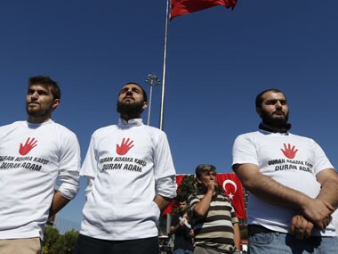 Men face people that gathered for a silent protest at Taksim Square in, Istanbul, Turkey. AP