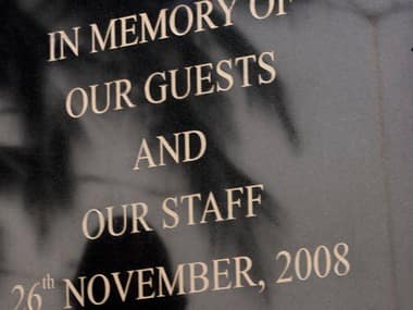 People are reflected on a memorial monument as they mark the first anniversary of the Mumbai attacks outside Oberoi and Trident hotel in Mumbai on 26 November 2009. Reuters